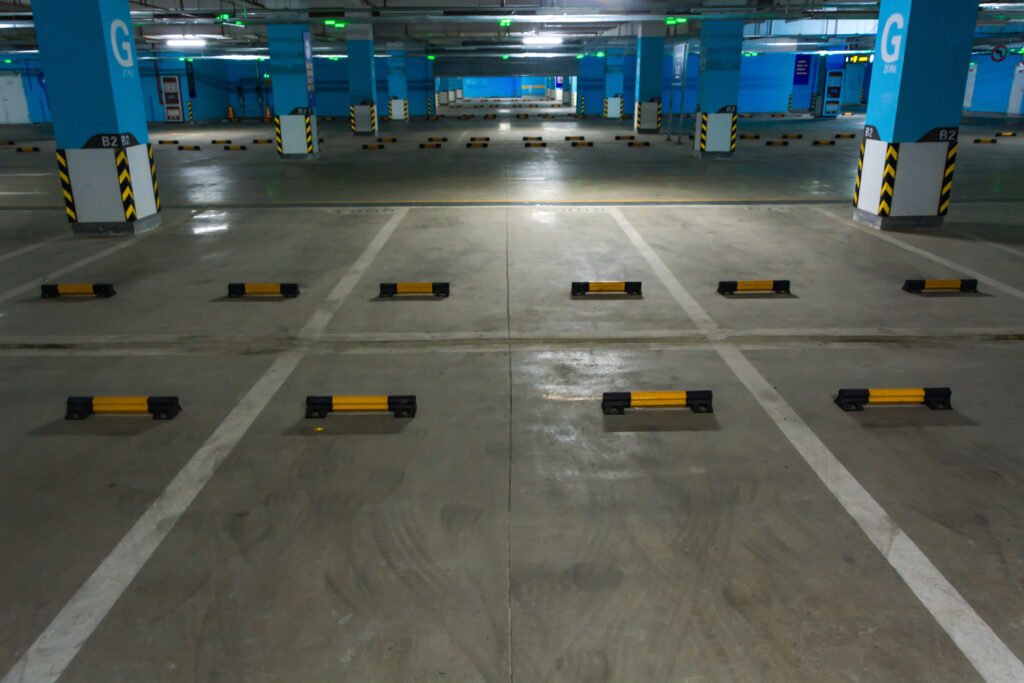 Empty underground parking garage with freshly painted parking lot stripes. Painted Wheel Stops as well. This is an industrial warehouse.